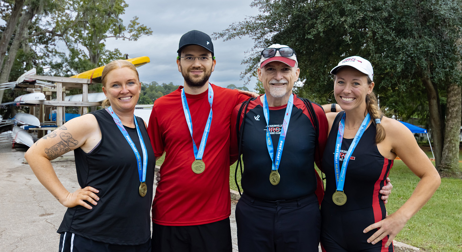 JRC racers posing for a group shot in front of their trailer loaded with rowing shells