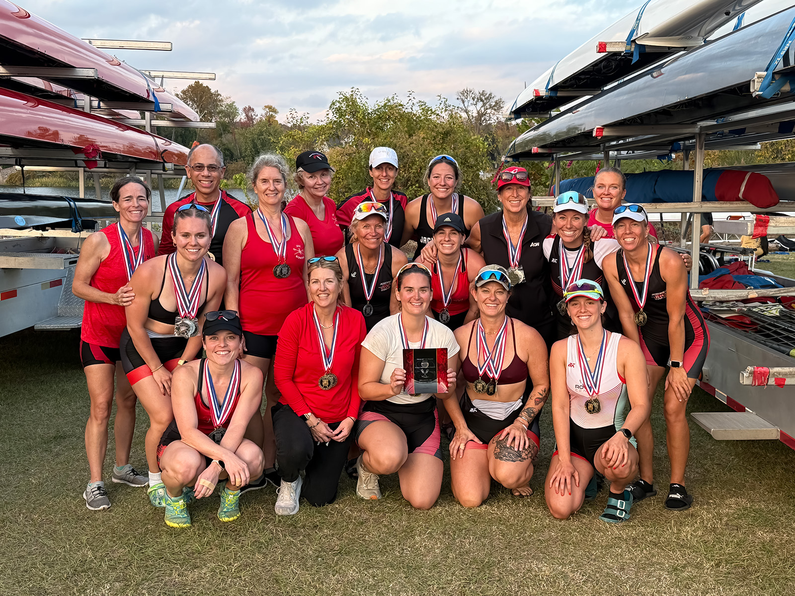 JRC racers posing for a group shot in front of their trailer loaded with rowing shells
